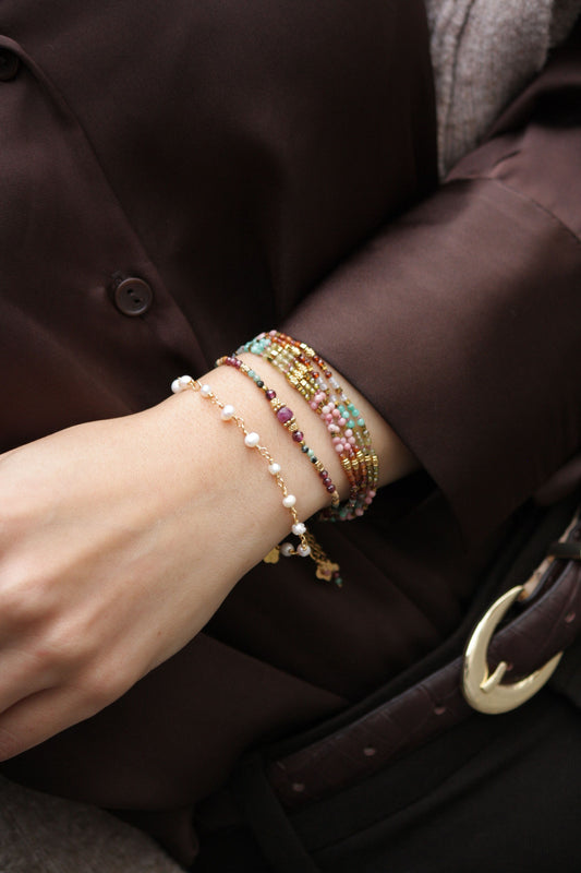 Stack of handcrafted gemstone bracelets featuring freshwater pearls, pink rhodochrosite, pink opal, and multi-layer beaded crystals