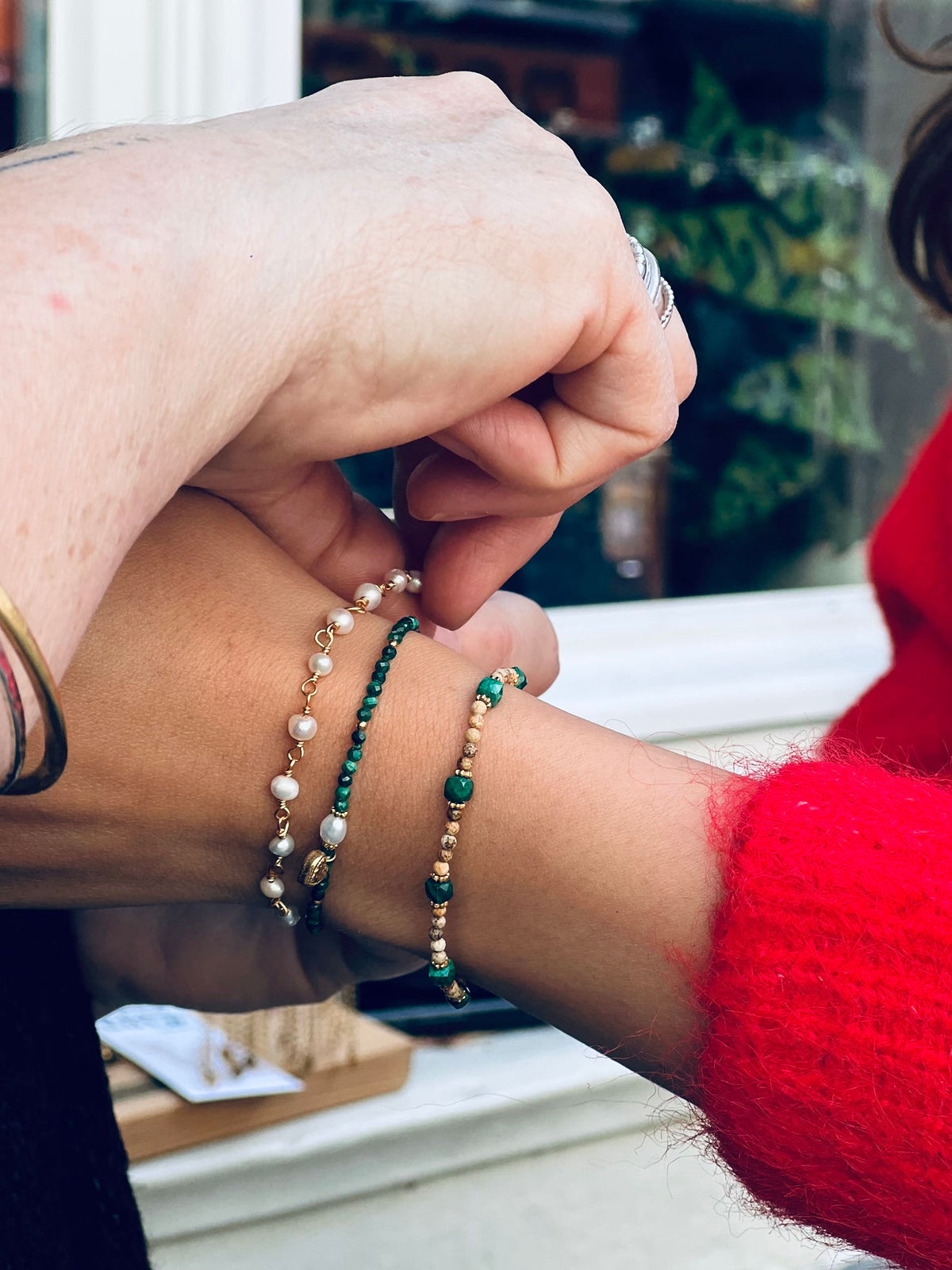 Stack of handcrafted gemstone bracelets with freshwater pearls, malachite heart, and beige jasper